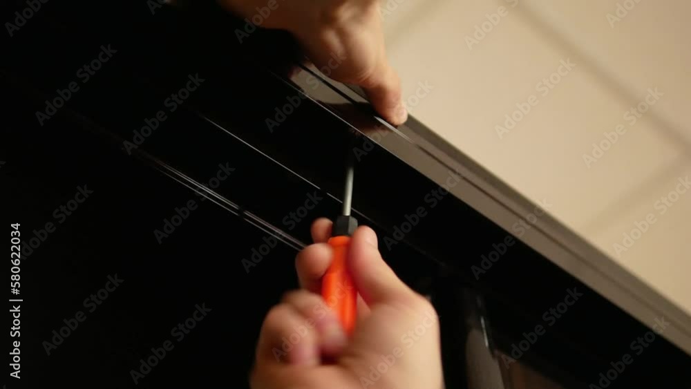 Man's hand assembles a closet with a screwdriver close-up Man's hand assembles a closet with a screwdriver close-up