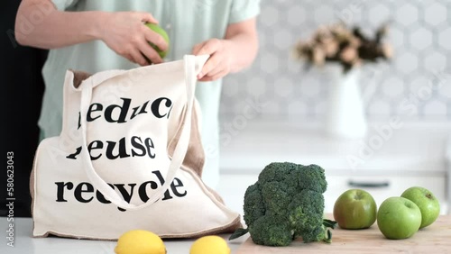 A young woman chooses a zero waste lifestyle. Woman takes out vegetable and fruits from bag after shopping. Waste Reduction and Reducing. Reusable cloth produce bag. Plastic alternatives for food