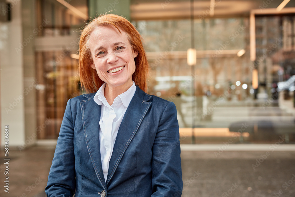 Fototapeta premium Successful middle-aged businesswoman smiling in front of luxury office.