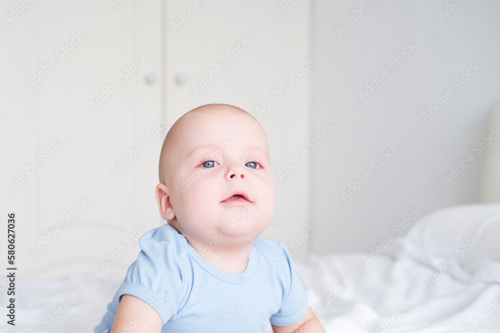 portrait of smiling baby boy with big blue eyes in bodysuit on white bedding. Healthy newborn child portrait of smiling baby boy with big blue eyes in bodysuit on white bedding. Healthy newborn child