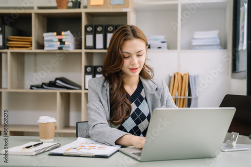 women hand working with laptop computer with documents on office desk in modern office.
