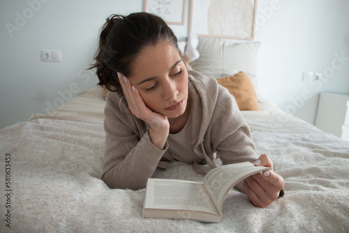 Woman relaxing on a bed reading a book