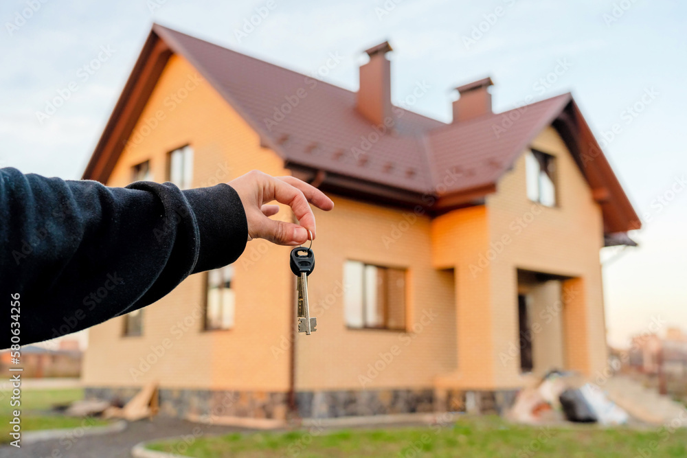 Hand holding key in front of home. Real estate, leasing insurance and purchase concept Hand holding key in front of home. Real estate, leasing insurance and purchase concept