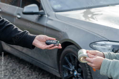 Deal of buying or renting car concept. Hand with car keys, other hand gives money.