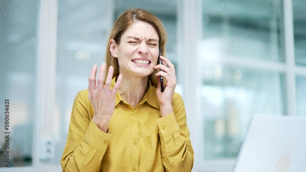 Portrait of angry irritated mature blond business woman holding smartphone and shouting yelling at microphone during conflict working call expressing negative emotion at modern glass workplace indoors Portrait of angry irritated mature blond business woman holding smartphone and shouting yelling at microphone during conflict working call expressing negative emotion at modern glass workplace indoors