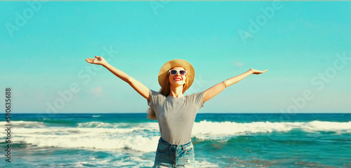 Summer vacation, happy smiling woman raising her hands up on the beach on sea background on sunny day
