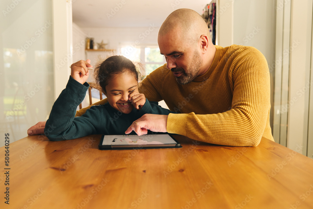 Multiracial father and son with Down syndrome using digital tablet for homework