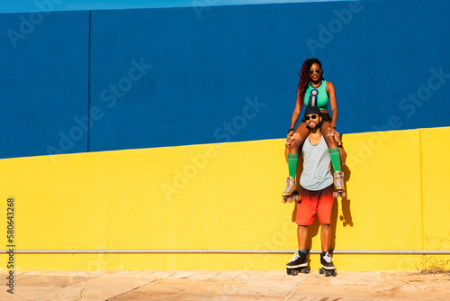 Cheerful couple with roller skating outside. Fun sexy boyfriend and girlfriend enjoy in sunny day..