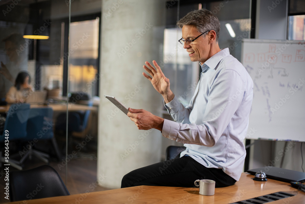 Fototapeta premium Portrait of businessman in office. Man using digital tablet. Businessman having video call.