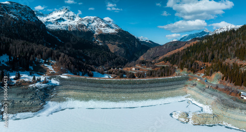 Aerial view of the water dam and reservoir lake in Swiss Alps mountains producing sustainable hydropower, hydroelectricity generation, renewable energy to limit global warming.