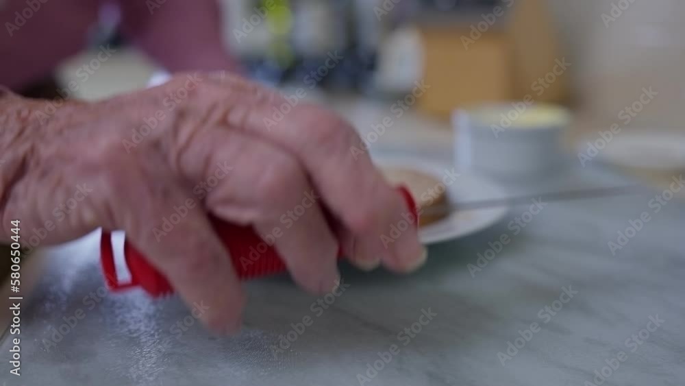 Close Up Of Senior Man With Arthritis In Kitchen Using Adapted Cutlery To Butter Bread Close Up Of Senior Man With Arthritis In Kitchen Using Adapted Cutlery To Butter Bread
