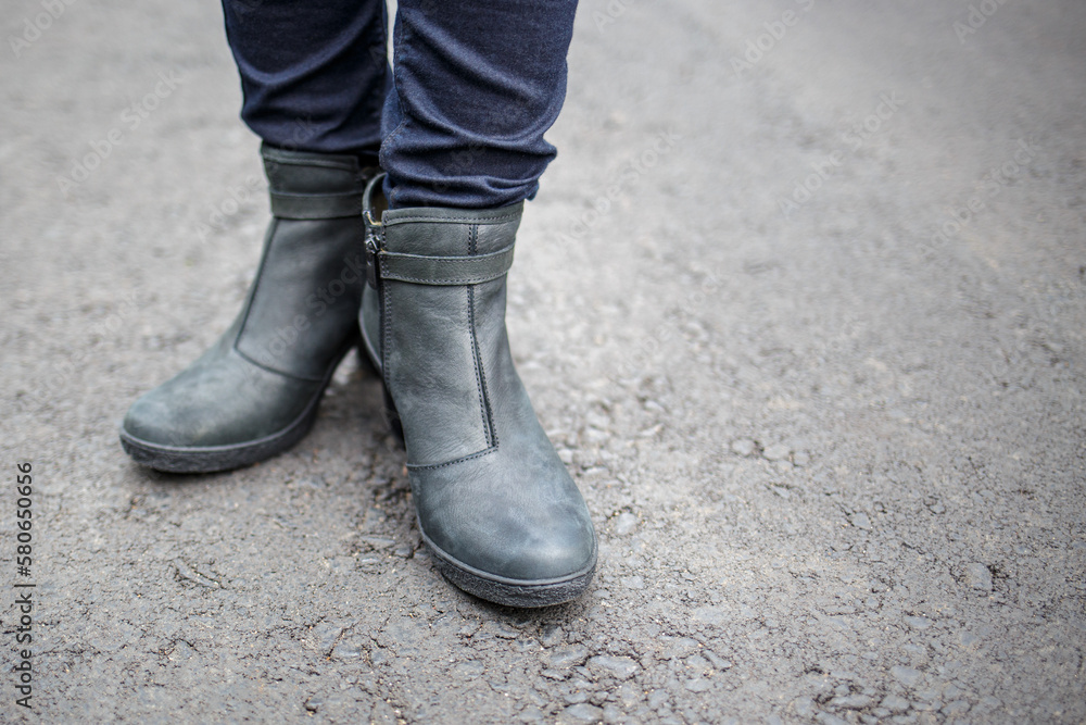 Young woman wearing nice boots standing on the asphalt surface. Young woman wearing nice boots standing on the asphalt surface.