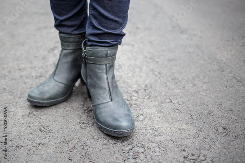 Young woman wearing nice boots standing on the asphalt surface.