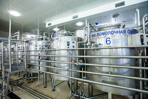 Modern milk factory tanks for yogurt and pipes. photo