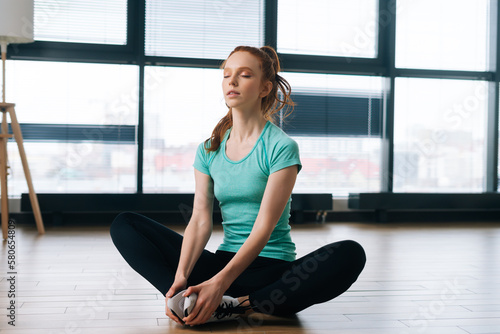 Free Download Portrait of sporty young woman practicing yoga, sitting in butterfly or konasana pose with closed eyes, stretching muscles on floor. Flexible fit female sitting on floor in lotus butterfly yoga pose - GFXLoad