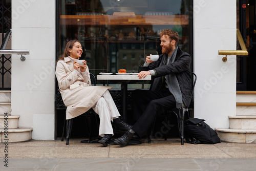 Canvas Print Happy couple drinking coffee and laughing talking to each other sitting at the t