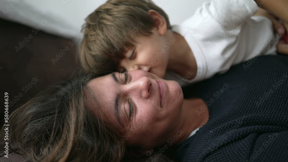 Mother and child love and affection. Little boy kissing mom on the lips. Family care and tenderness. Kid and mom together lying on couch Mother and child love and affection. Little boy kissing mom on the lips. Family care and tenderness. Kid and mom together lying on couch