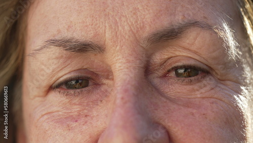 Happy senior woman macro eyes close up looking at camera. Wrinkled female person in 70s aged expression