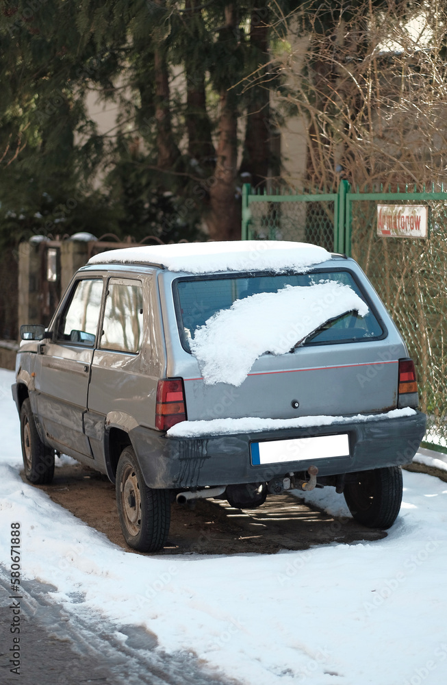 Gdynia, Poland - 03 10 2023: Tiny retro car abandoned on the street close-up during snowy weather. Gdynia, Poland - 03 10 2023: Tiny retro car abandoned on the street close-up during snowy weather.