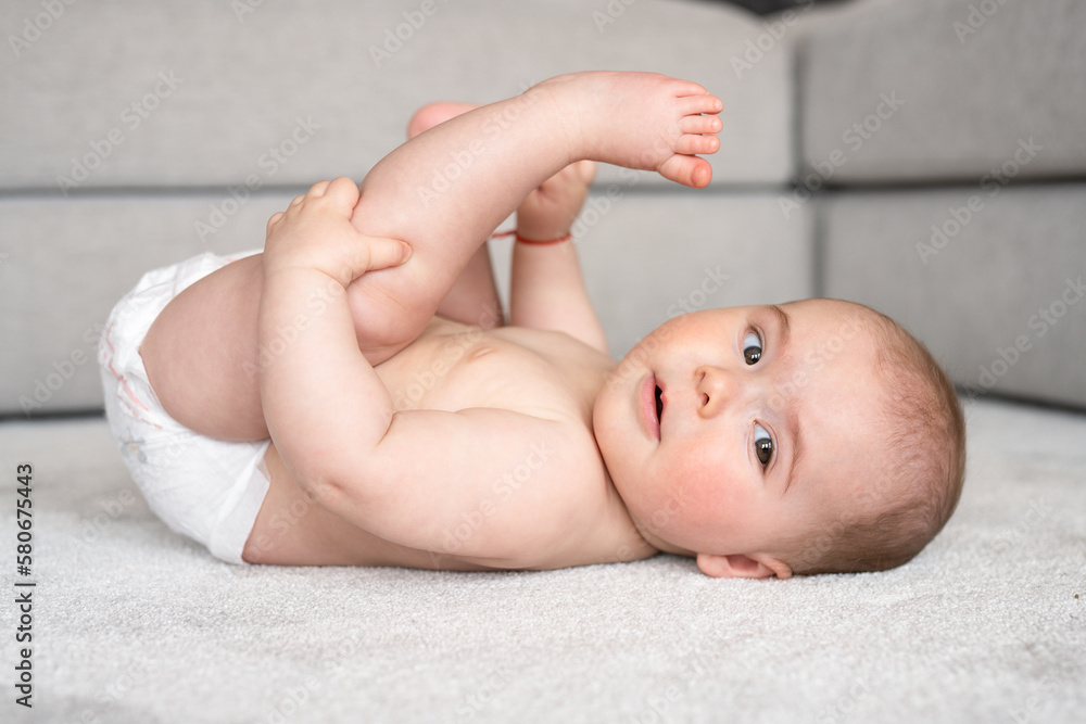 childhood, babyhood and people concept - happy little baby boy or girl lying on floor at home childhood, babyhood and people concept - happy little baby boy or girl lying on floor at home