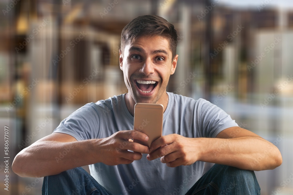 Smiling young man holding phone, using smartphone Smiling young man holding phone, using smartphone