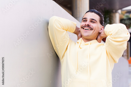 young cool man smiling and feeling relaxed, satisfied and carefree, laughing positively and chilling