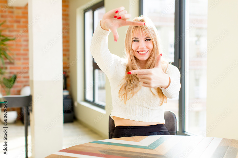 young pretty woman feeling happy, friendly and positive, smiling and making a portrait or photo frame with hands. home interior young pretty woman feeling happy, friendly and positive, smiling and making a portrait or photo frame with hands. home interior