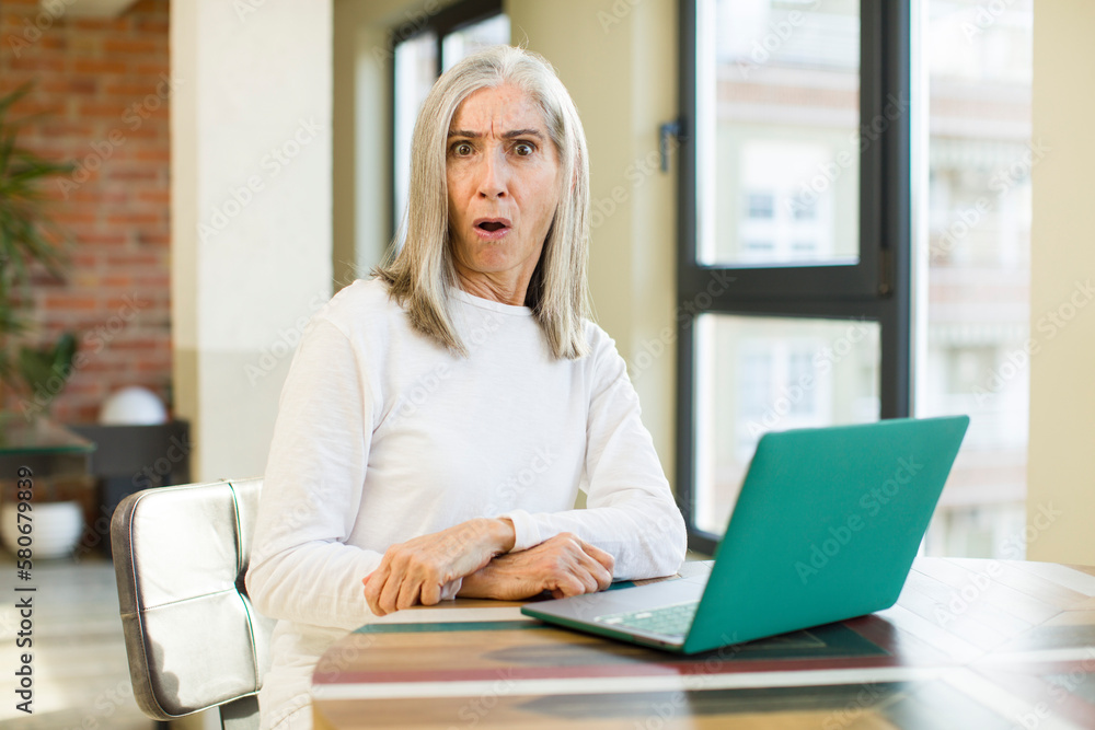senior pretty woman feeling extremely shocked and surprised with a laptop senior pretty woman feeling extremely shocked and surprised with a laptop