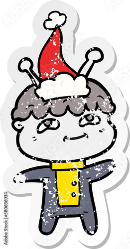 friendly distressed sticker cartoon of a spaceman wearing santa hat