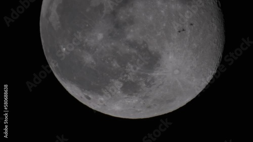 Migrating birds fly in the night sky with a full moon.