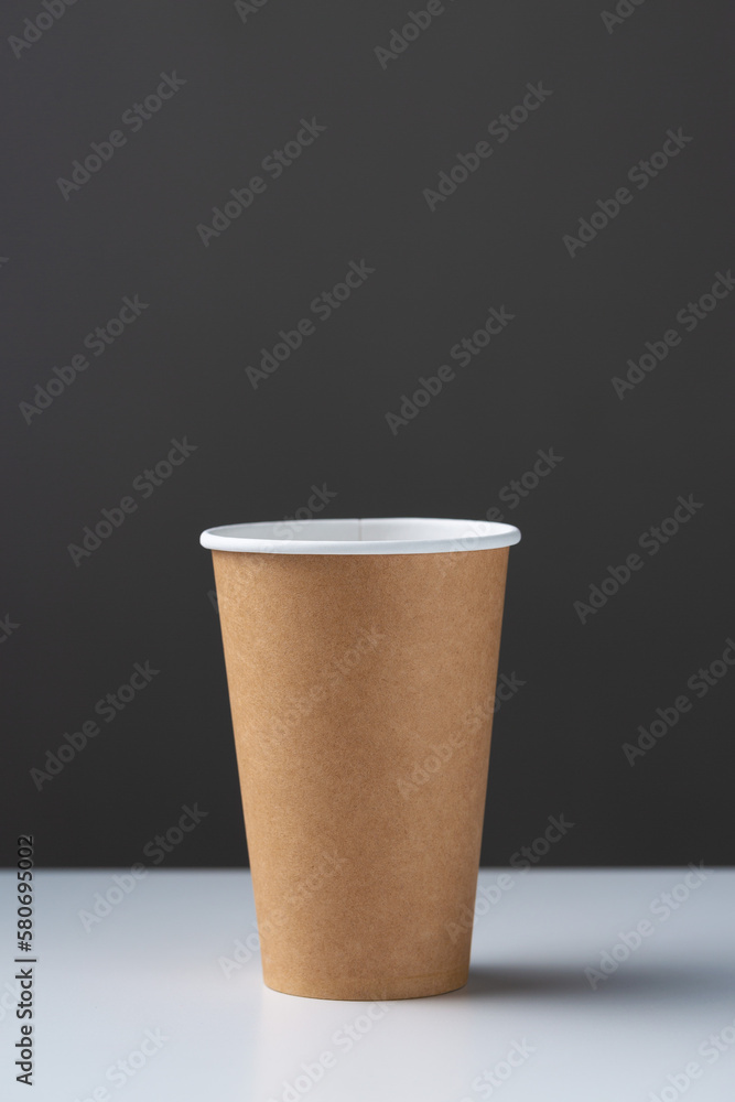 Disposable cardboard biodegradable glass on a white table, gray background. Disposable cardboard biodegradable glass on a white table, gray background.