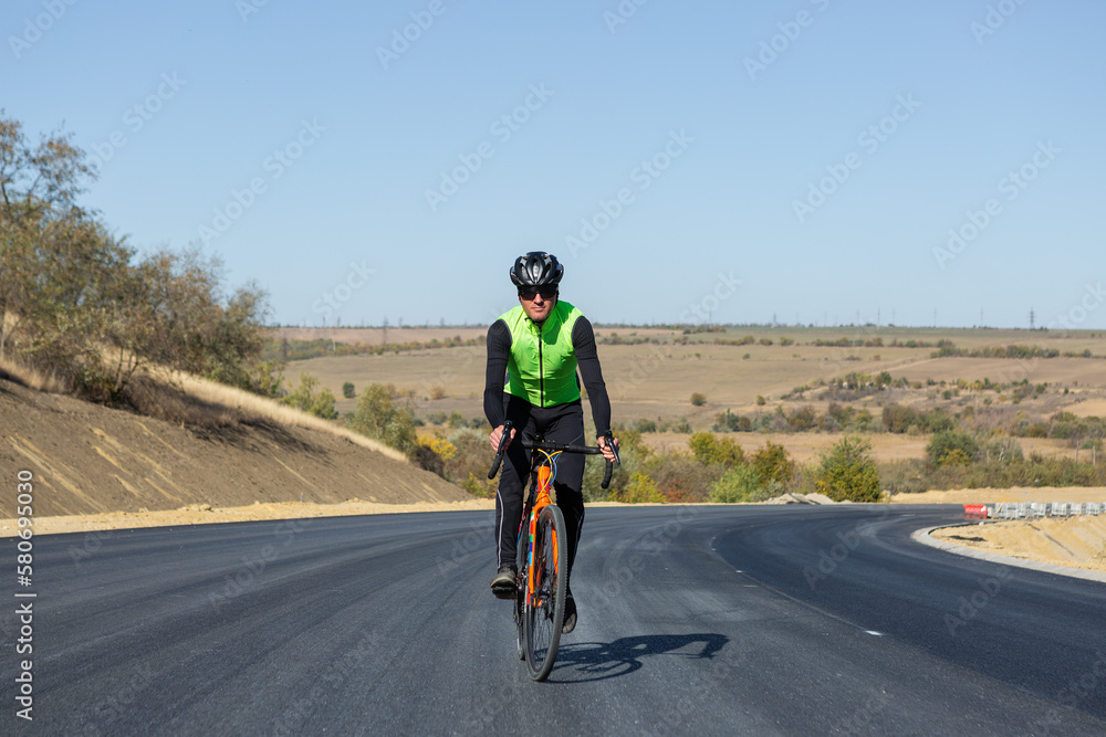 Obraz premium Cyclist riding bicycle on road against clear sky