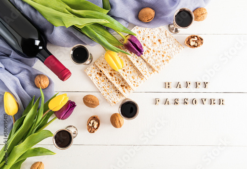 festive background with traditional treats for the jewish Passover holiday. White wooden background with happy passover letters and flowers.