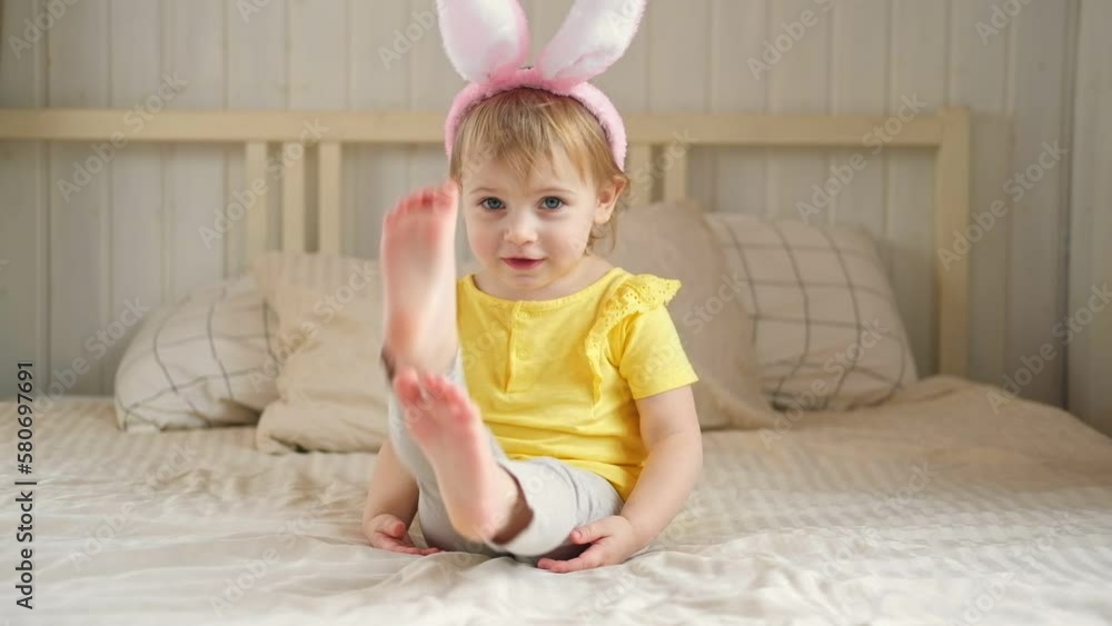 Baby girl with bunny ears. Cute funny baby play Easter eggs at home. Child playing colorful eggs indoors. Spring. Little kid celebrating Easter with traditional symbol of holiday and religion concept Baby girl with bunny ears. Cute funny baby play Easter eggs at home. Child playing colorful eggs indoors. Spring. Little kid celebrating Easter with traditional symbol of holiday and religion concept