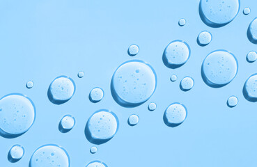 round drops of transparent gel serum on blue background