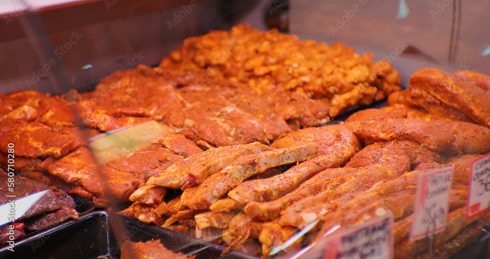 Large range of seasoned meat with spices and herbs in showcase in shop. Close up meat prepared for barbecue.
