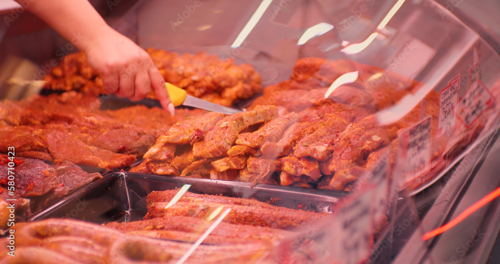 Woman hands picking piece of seasnoed meat with a butchers knife. Meat industry selling pre-prepared products out of diverse meat. Woman hands picking piece of seasnoed meat with a butchers knife. Meat industry selling pre-prepared products out of diverse meat.