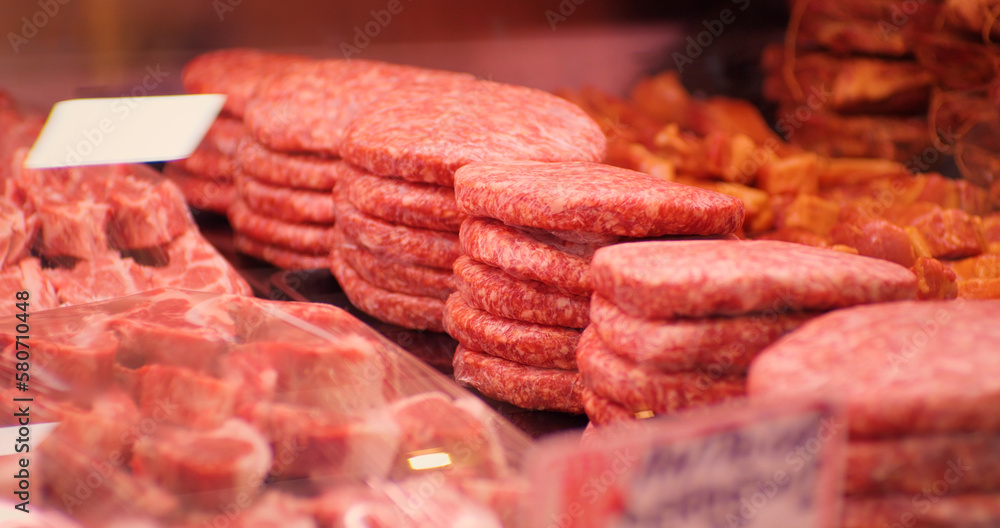 Beef burgers and other meat preps ready to be sold. Food industry. Raw minced meat beef burger cutlets in a window shop. Beef burgers and other meat preps ready to be sold. Food industry. Raw minced meat beef burger cutlets in a window shop.