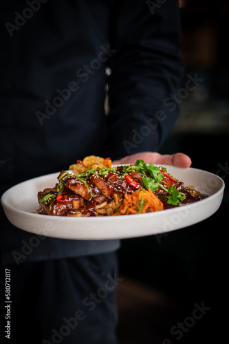 Fototapeta Naklejka Na Ścianę i Meble -  chef hand hold plate whith Stewed pork slice with noodles and vegetables