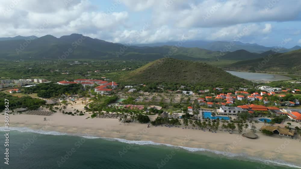 Aerial panoramic view of the Puerto Cruz beach on the Margarita island at dawn. Sandy coast with all inclusive resorts and lighthouse on the cliff. Vacation in Venezuela Aerial panoramic view of the Puerto Cruz beach on the Margarita island at dawn. Sandy coast with all inclusive resorts and lighthouse on the cliff. Vacation in Venezuela