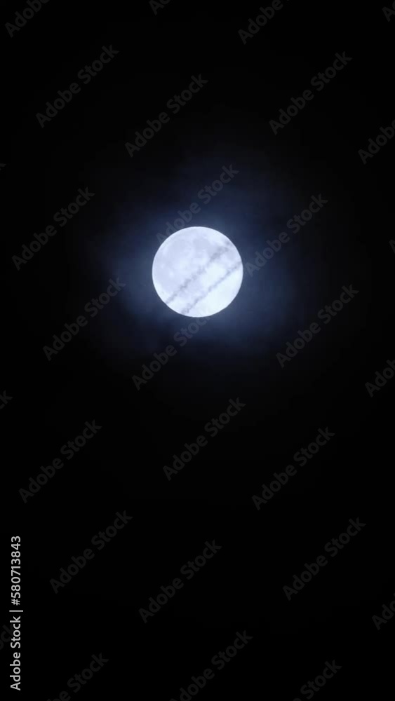 Airplane crossing the moon at night with trail. Telephoto view of a passenger jet flying against the bright full moon on the mysterious cloudy sky. Plane silhouette, black background and copy space. Airplane crossing the moon at night with trail. Telephoto view of a passenger jet flying against the bright full moon on the mysterious cloudy sky. Plane silhouette, black background and copy space.