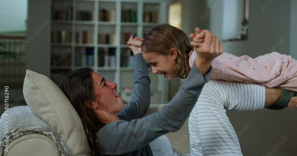 Portrait of Young Woman Playing with her Daughter During Evening in the Living Room. Little Cute Girl Bonding with her Mother, Enjoying her Time and Laughing While Pretending that She Can Fly Portrait of Young Woman Playing with her Daughter During Evening in the Living Room. Little Cute Girl Bonding with her Mother, Enjoying her Time and Laughing While Pretending that She Can Fly