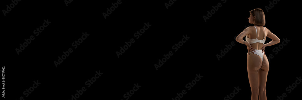 Back view of female body in white inner wear isolated over dark background. Anti-cellulite care cosmetology. Concept of beauty, body care, health, plastic surgery Back view of female body in white inner wear isolated over dark background. Anti-cellulite care cosmetology. Concept of beauty, body care, health, plastic surgery