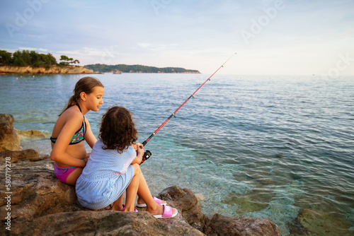 Happy children enjoying leisure day, fishing on the idyllic rocky beach, basking in the summertime sun and exploring all that nature has to offer.