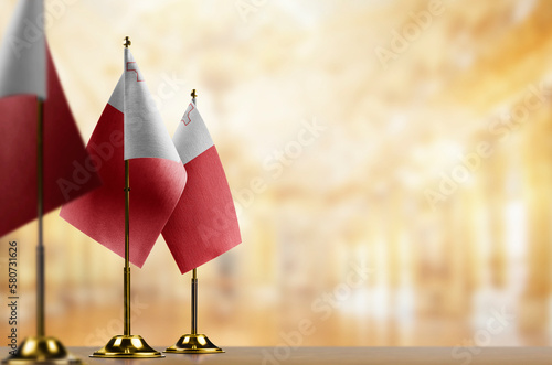 Small flags of the Malta on an abstract blurry background
