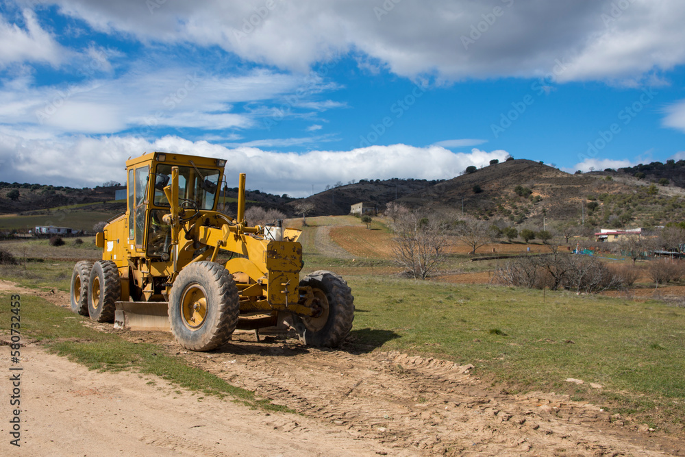 A tractor is used to remove dirt from a dirt road. A tractor is used to remove dirt from a dirt road.