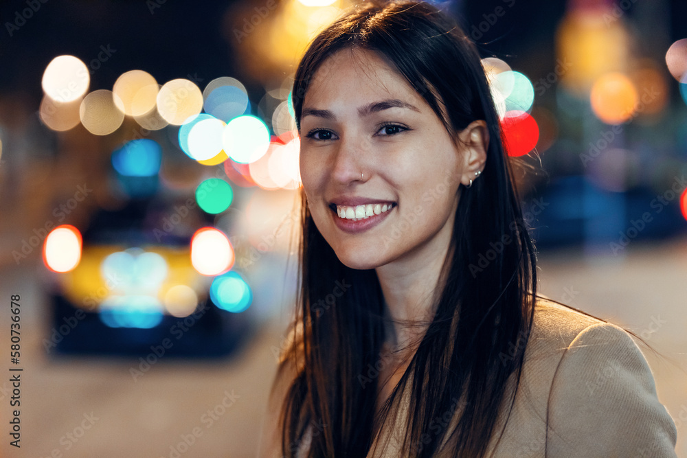 Attractive smiling young woman walking in the street at night.