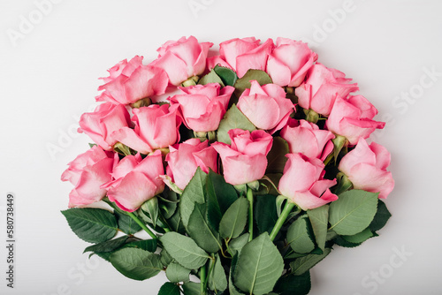 Beautiful bunch of fresh pink roses in full bloom on white background. Bouquet of flowers, flat lay. Valentine's day or Mother's day card. photo