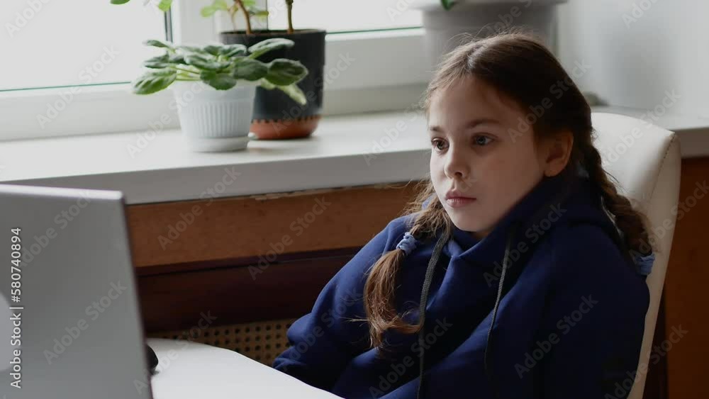 A little girl in a blue suit looks at the computer screen with downcast eyes. Children on the Internet, information security. A little girl in a blue suit looks at the computer screen with downcast eyes. Children on the Internet, information security.