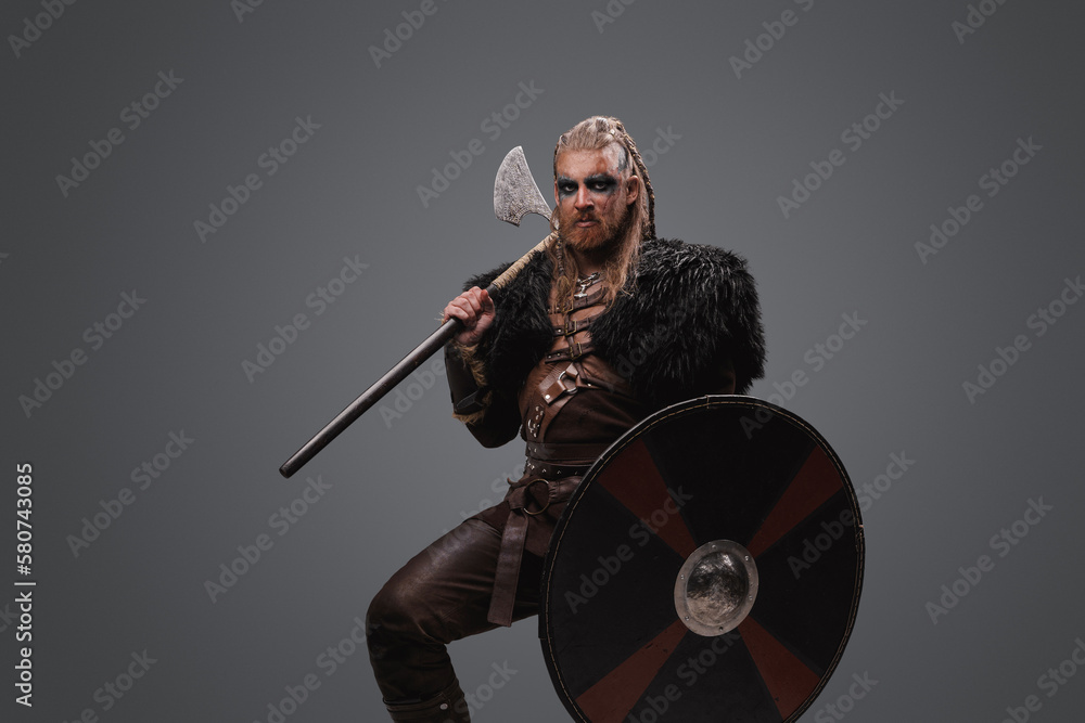Studio shot of fearful nordic barbarian with axe with shield dressed in black fur. Studio shot of fearful nordic barbarian with axe with shield dressed in black fur.